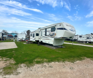 rv concrete site with green grass around it. White RV with spacious sites